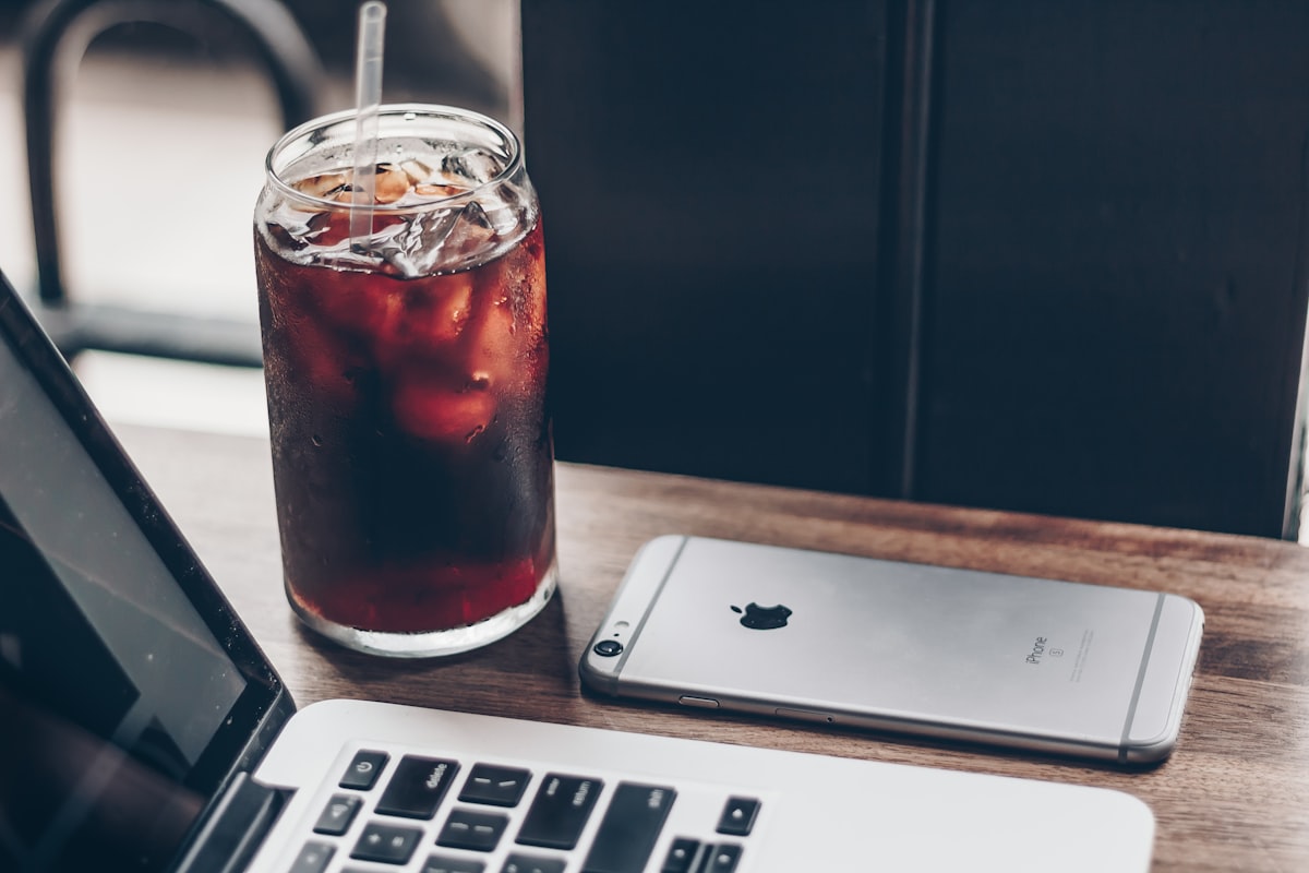 Laptop y teléfono sobre una mesa de café durante una jornada de trabajo